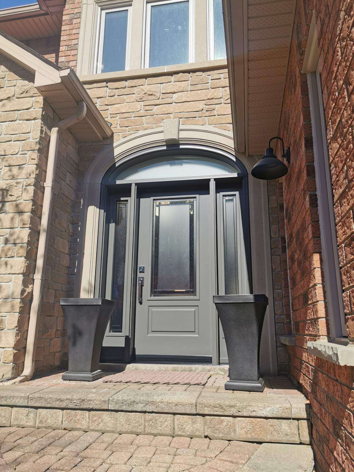 Energy-efficient white entry door with arched transom window on Winnipeg stone brick home