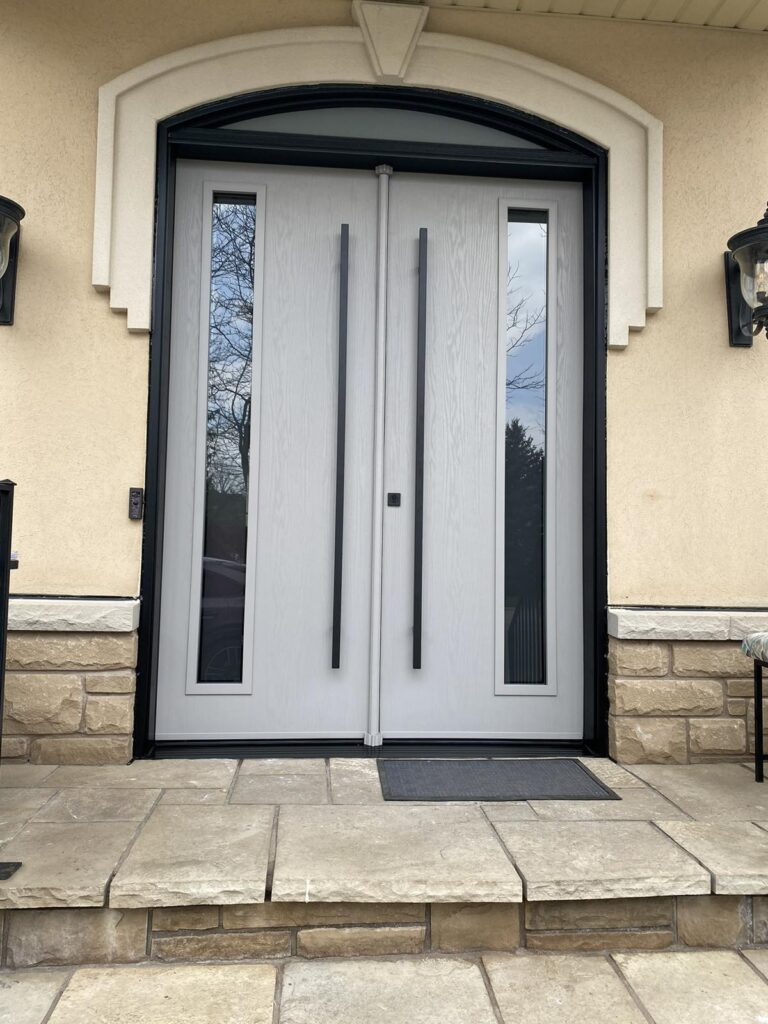 Modern double front entry doors with vertical glass inserts installed on Winnipeg home with stone steps and arched frame
