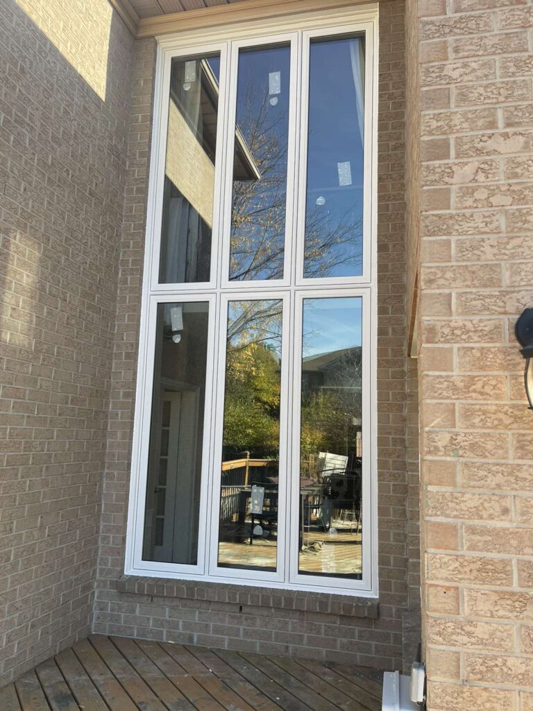 White vinyl large two-storey picture window with six-panel fixed frame installed on Winnipeg brick home exterior