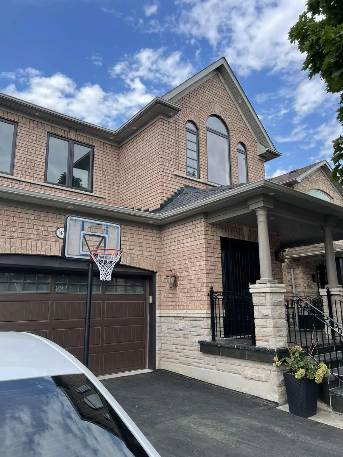 Brick home in Winnipeg with newly installed black-trim casement and arched windows above garage
