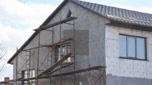 Exterior of a home under renovation with scaffolding and window installation in progress, showing ideal spring conditions, highlighting the best time of year to install new windows in Winnipeg.